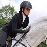 Rider wears the Shires Karben Elisa Ellipse Wide Peak Riding Hat in Black/Black